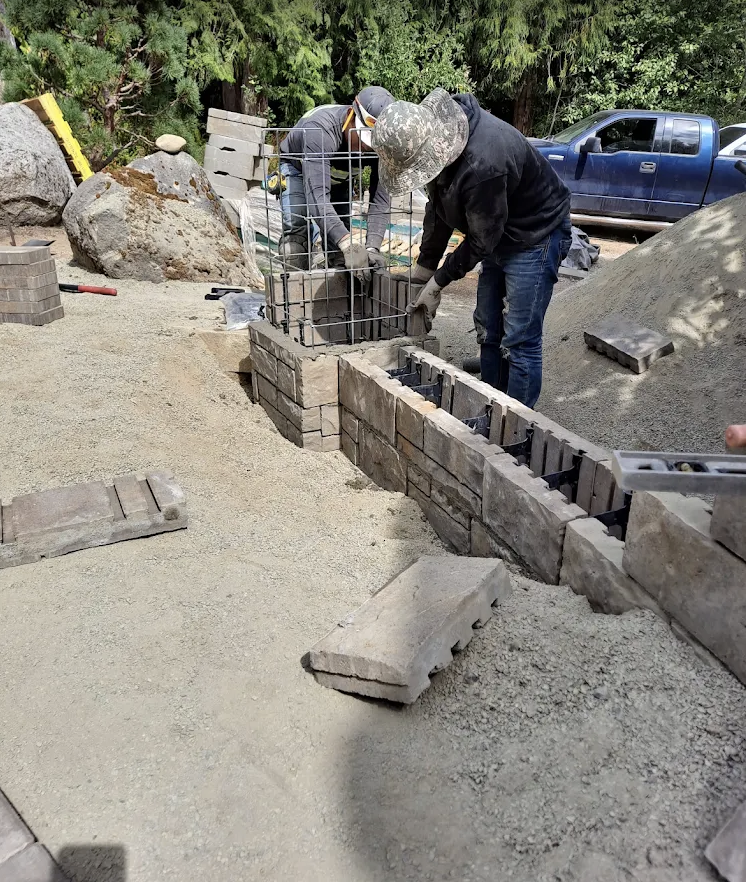 Crew setting segmental blocks and steel reinforcement for a new retaining wall