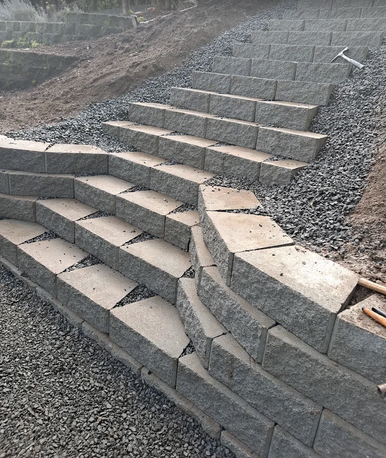 Block retaining wall steps built into a slope on a compacted gravel base