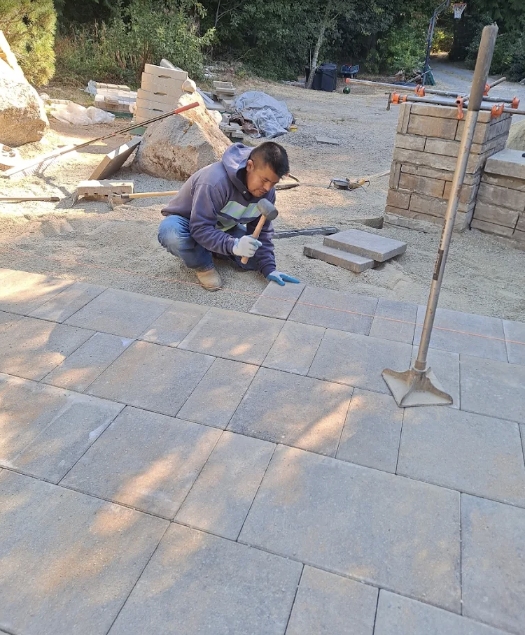 Crew member tapping in a paver with a rubber mallet on a screeded base