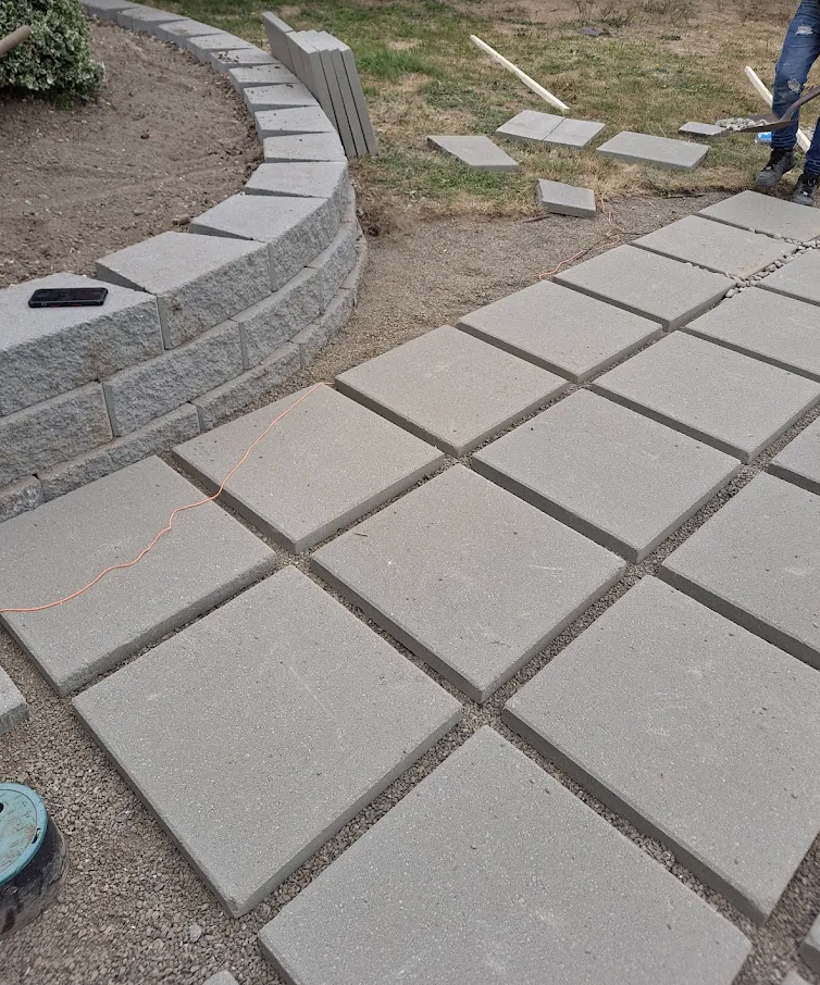 Square paver walkway going in beside a curved block seat wall