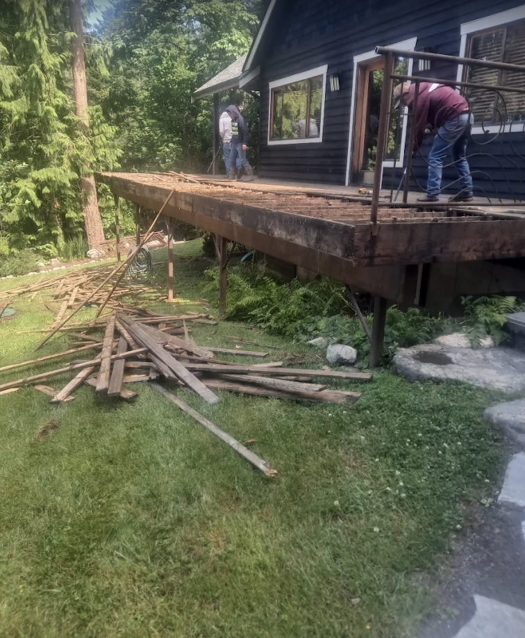Old decking stripped down to the frame with boards stacked on the lawn